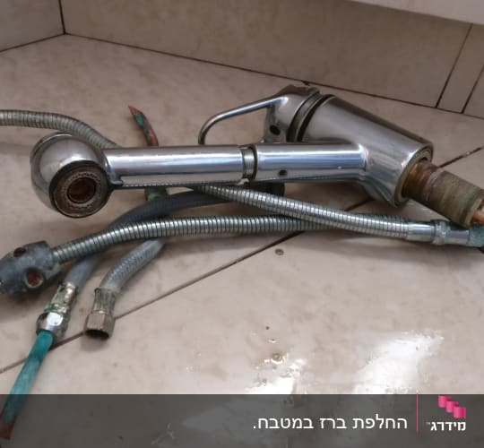 ברז וכמה צינורות מתכת על רצפה רטובה